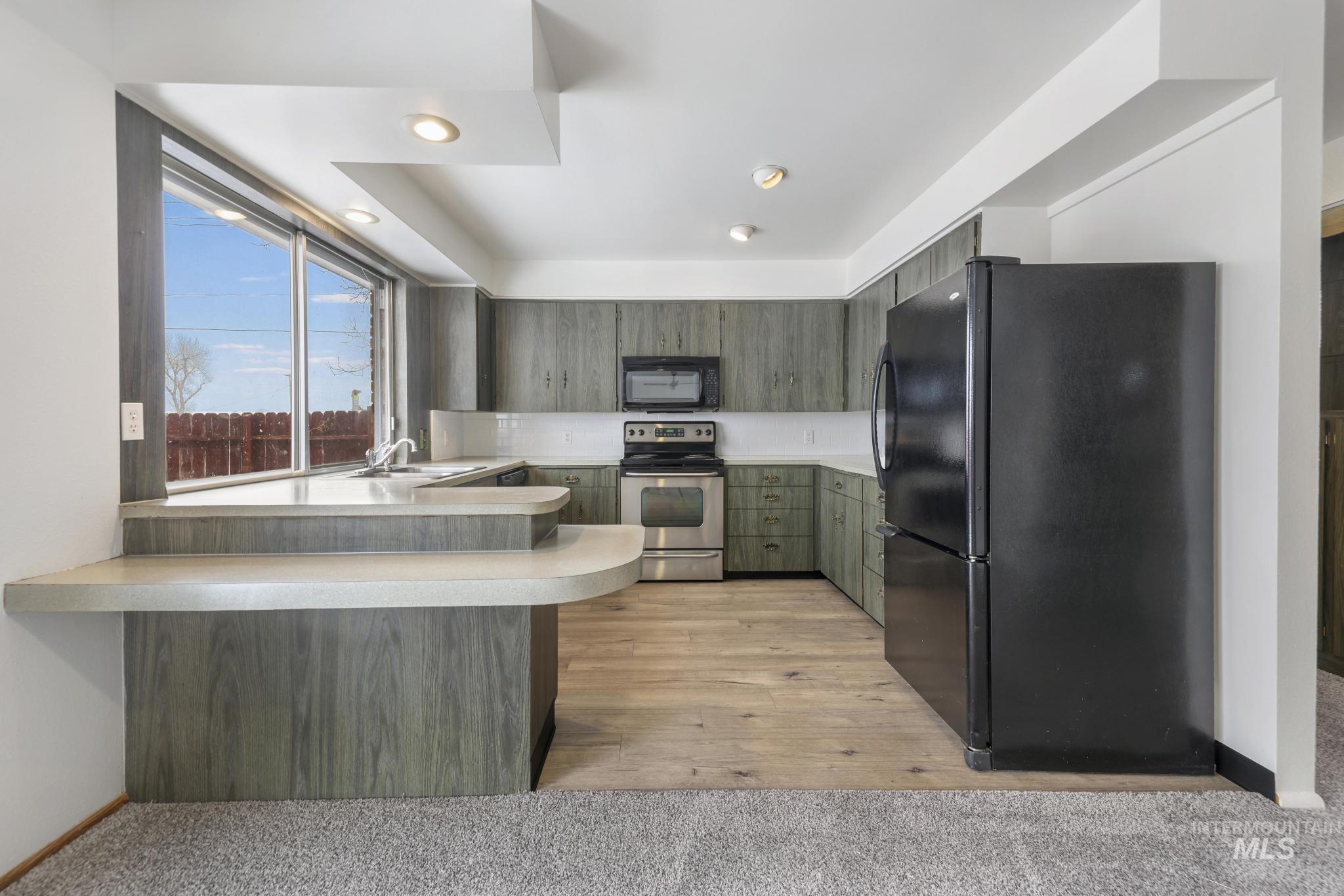 409 Clear Lakes Road Buhl, ID 83316 - Photo 7 of 43 Kitchen with black appliances, light countertops, a peninsula, recessed lighting, and light colored carpet