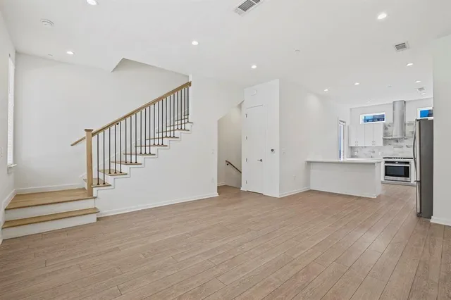 a view of an empty room with wooden floor and stairs