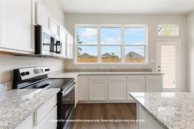 a kitchen with stainless steel appliances granite countertop a stove a sink and a microwave