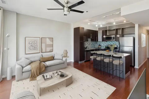 a living room with furniture kitchen view and a wooden floor