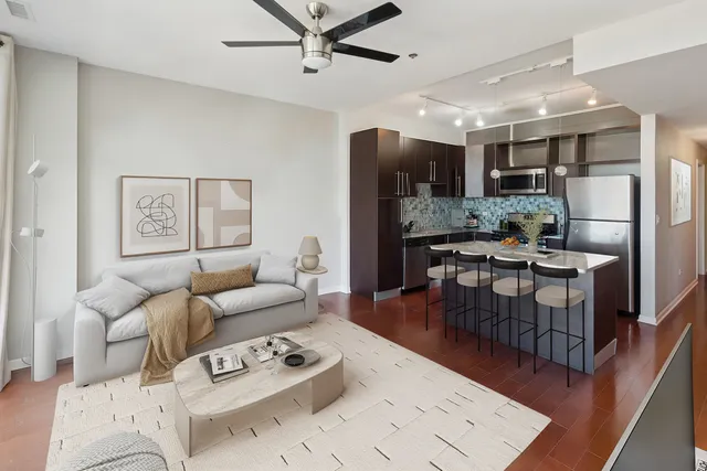 a living room with furniture kitchen view and a wooden floor