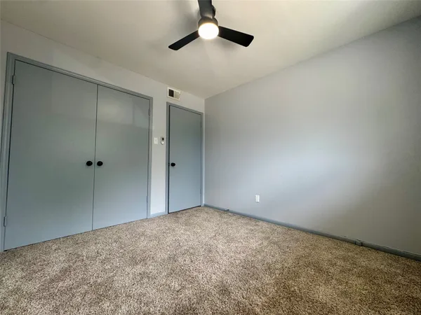 an empty room with a ceiling fan and window