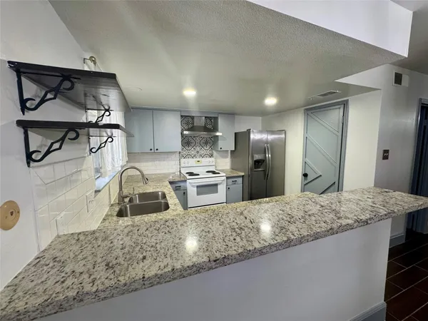 a kitchen with stainless steel appliances granite countertop a sink refrigerator and cabinets