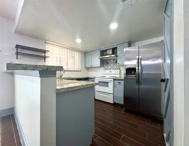 a kitchen with stainless steel appliances granite countertop a refrigerator and a stove top oven