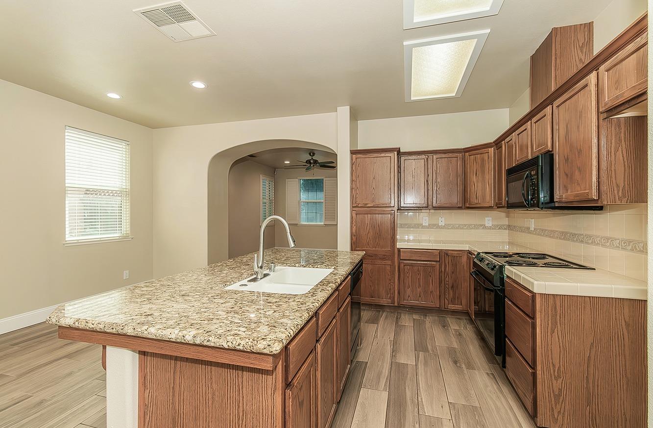 735 West Brittany Lane Clovis, CA 93619 - Photo 9 of 30 a kitchen with kitchen island granite countertop a sink stove and cabinets