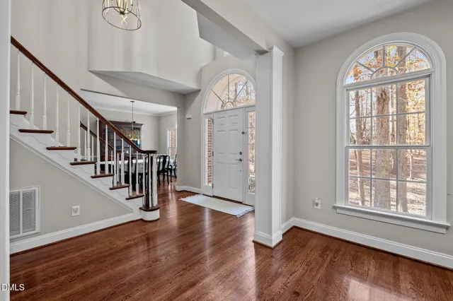 a view of an empty room with wooden floor and stairs