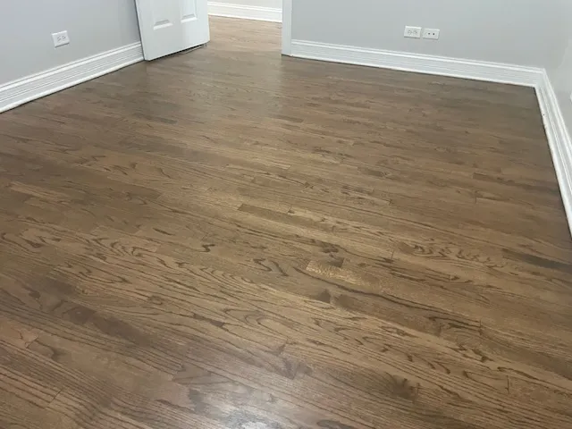 a view of an empty room with wooden floor and closet