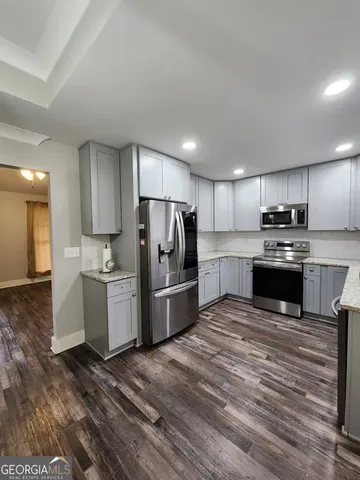 a kitchen with granite countertop a refrigerator and a stove top oven