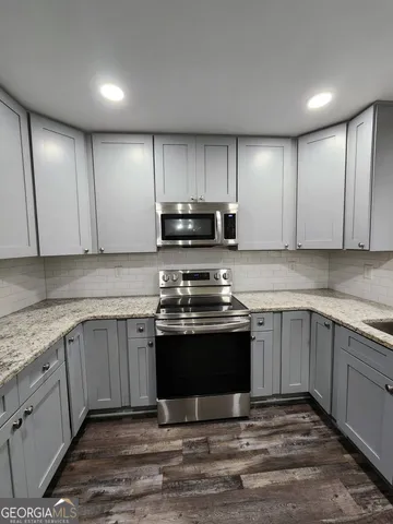 a kitchen with stainless steel appliances granite countertop a stove a sink and a microwave