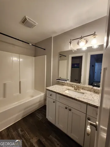 a bathroom with a granite countertop sink mirror and a bathtub