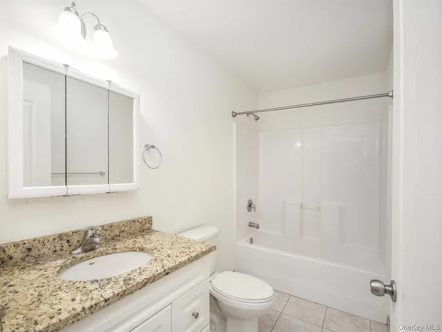 a bathroom with a granite countertop sink a toilet and shower