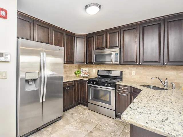 a kitchen with granite countertop stainless steel appliances cabinets a sink and a counter top space