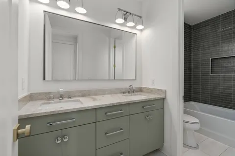a bathroom with a granite countertop sink a toilet and a mirror