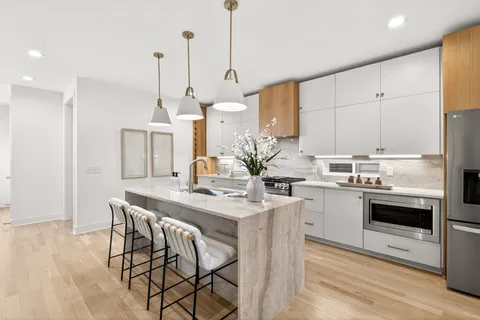 a kitchen with stainless steel appliances kitchen island a stove a table and chairs in it