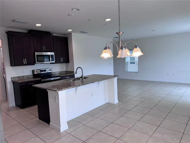 a kitchen with stainless steel appliances granite countertop a stove a sink and a microwave