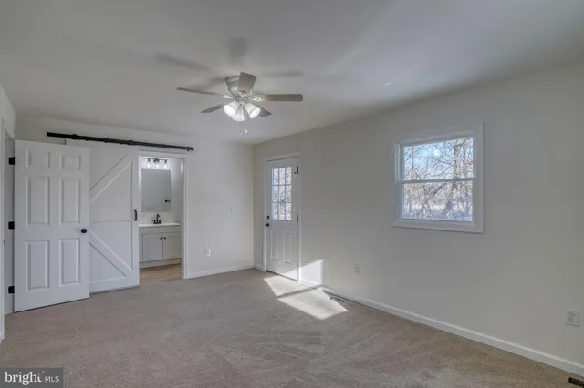 an empty room with chandelier fan and windows