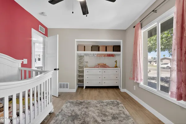 a view of a bedroom with baby crib and a window