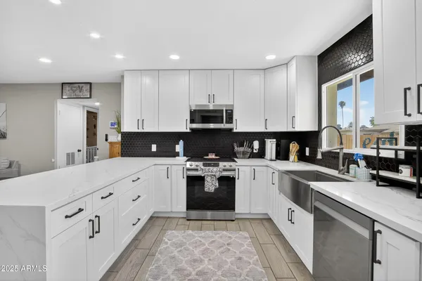 a kitchen with granite countertop white cabinets and stainless steel appliances