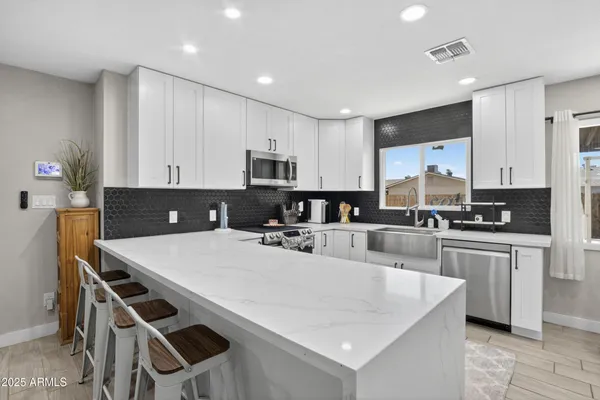 a large white kitchen with stainless steel appliances