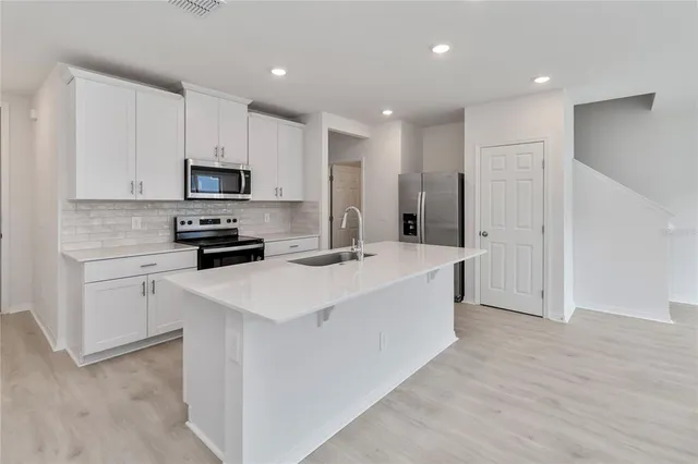 a kitchen with stainless steel appliances a sink a stove a refrigerator and cabinets