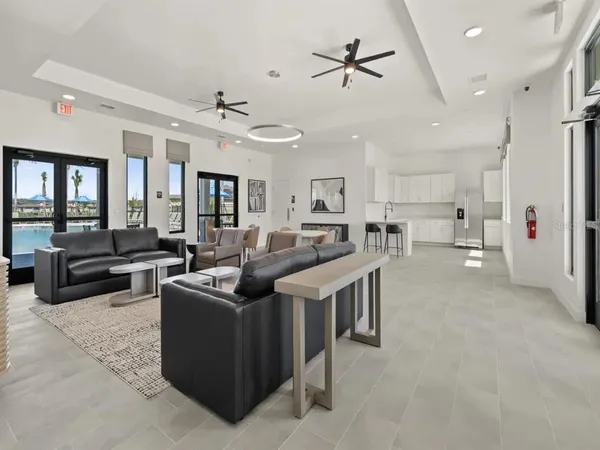 a living room with couches and kitchen view with wooden floor