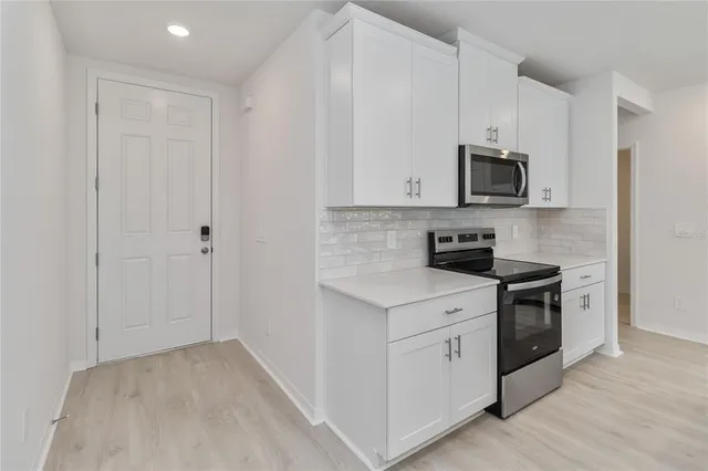 a kitchen with white cabinets and stainless steel appliances
