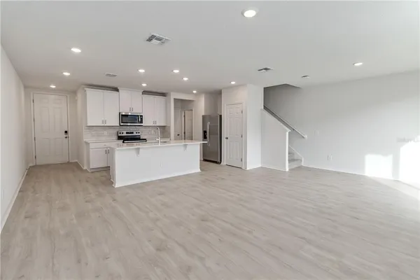 a view of kitchen with kitchen island a sink wooden floor and stainless steel appliances