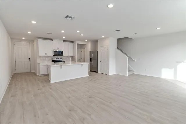 a view of kitchen with kitchen island a sink wooden floor and stainless steel appliances