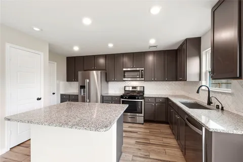 a kitchen with stainless steel appliances granite countertop a sink stove and refrigerator