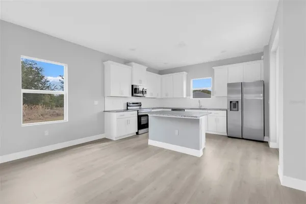 a kitchen with white cabinets and appliances