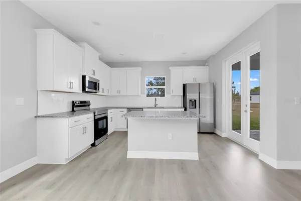a kitchen with granite countertop white cabinets and stainless steel appliances