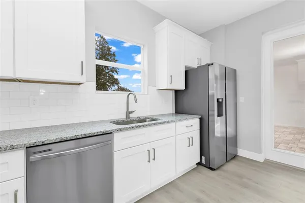 a kitchen with stainless steel appliances granite countertop a sink and a refrigerator