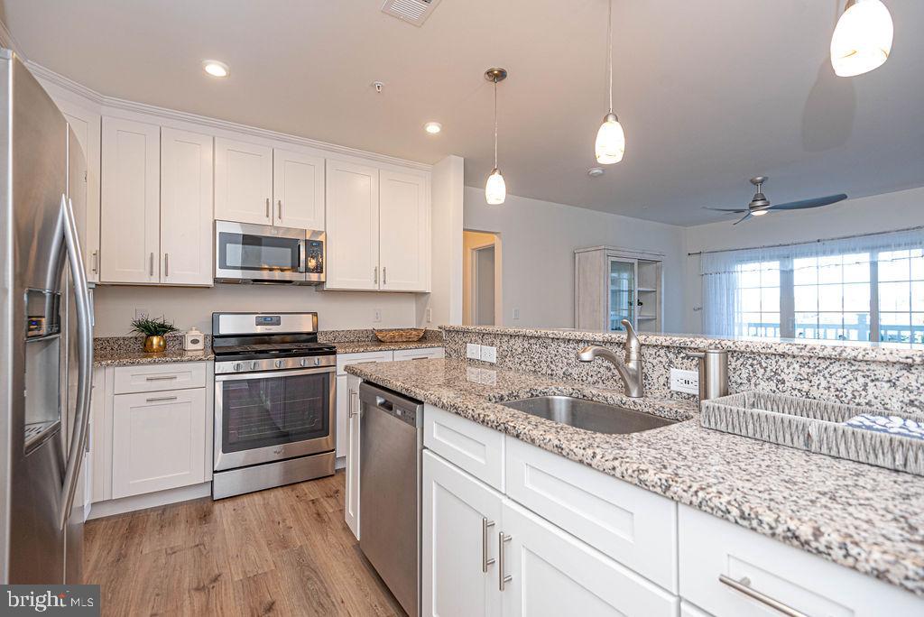 20141 Riesling Lane, Unit 106 Lewes, DE 19958 - Photo 15 of 31 a kitchen with stainless steel appliances granite countertop a sink a stove and a granite counter tops
