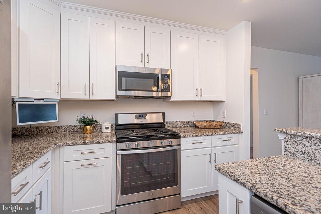 20141 Riesling Lane, Unit 106 Lewes, DE 19958 - Photo 16 of 31 a kitchen with granite countertop white cabinets and stainless steel appliances