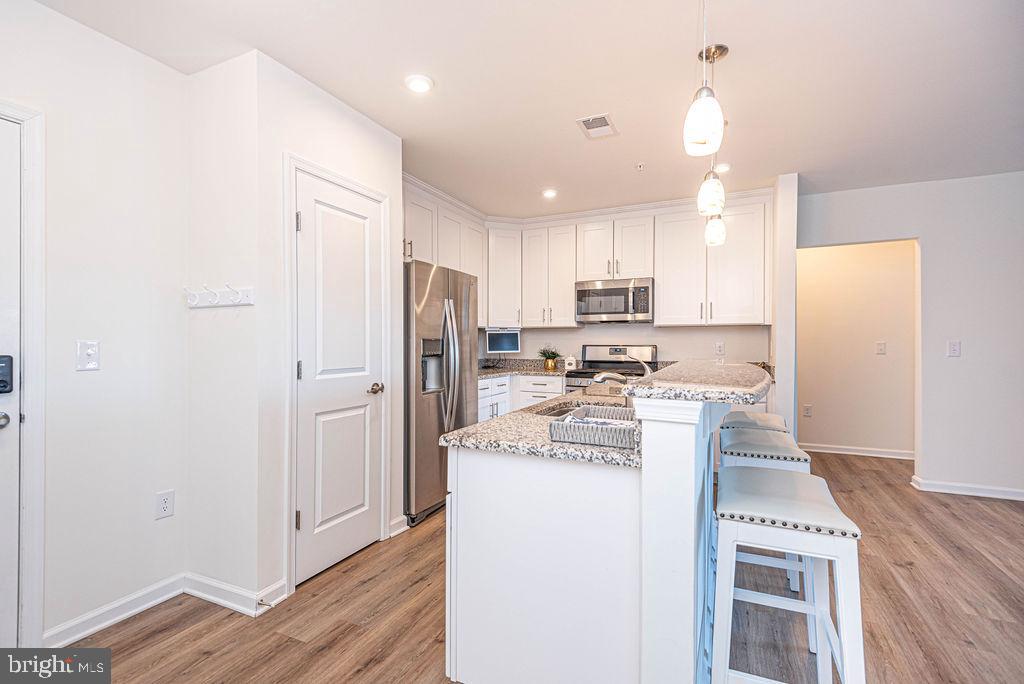 20141 Riesling Lane, Unit 106 Lewes, DE 19958 - Photo 7 of 31 a kitchen with refrigerator a microwave and cabinets