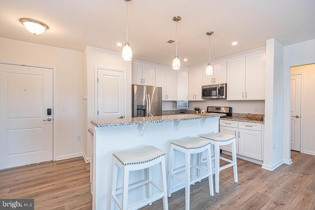20141 Riesling Lane, Unit 106 Lewes, DE 19958 - Photo 9 of 31 a kitchen with stainless steel appliances granite countertop a white cabinets and wooden floor