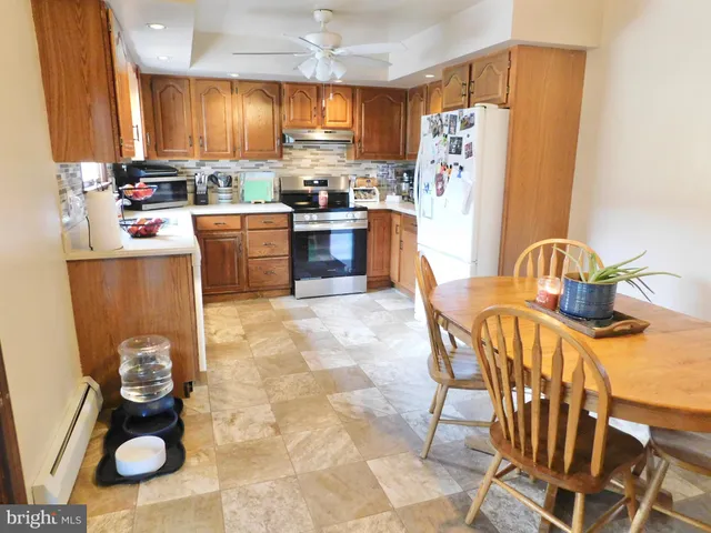 a kitchen with stainless steel appliances a sink a stove a refrigerator cabinets and dining table