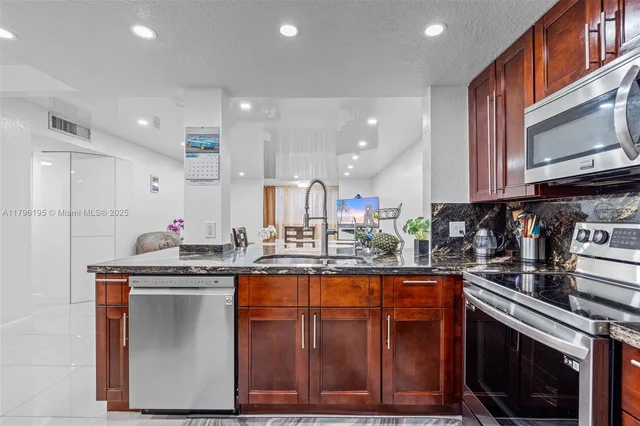 a kitchen with stainless steel appliances granite countertop a stove a sink and a microwave