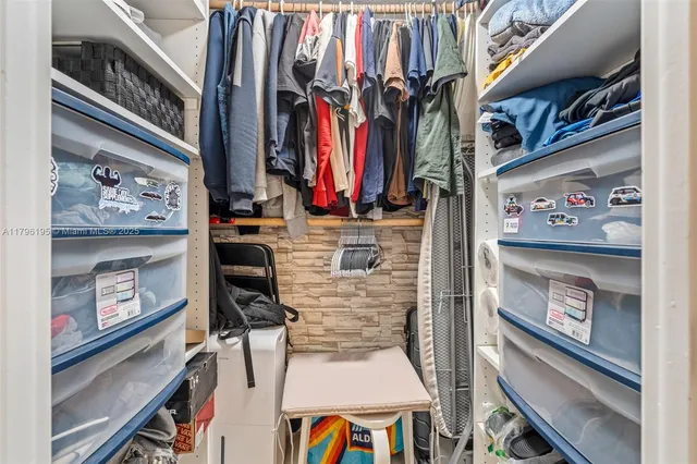 a view of walk in closet with clothes and shoes