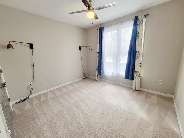 an empty room with windows and fan