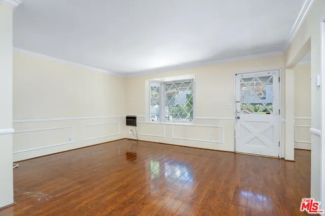 an empty room with wooden floor door and windows