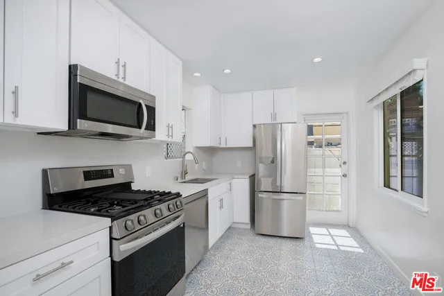 a kitchen with granite countertop white cabinets stainless steel appliances and a sink