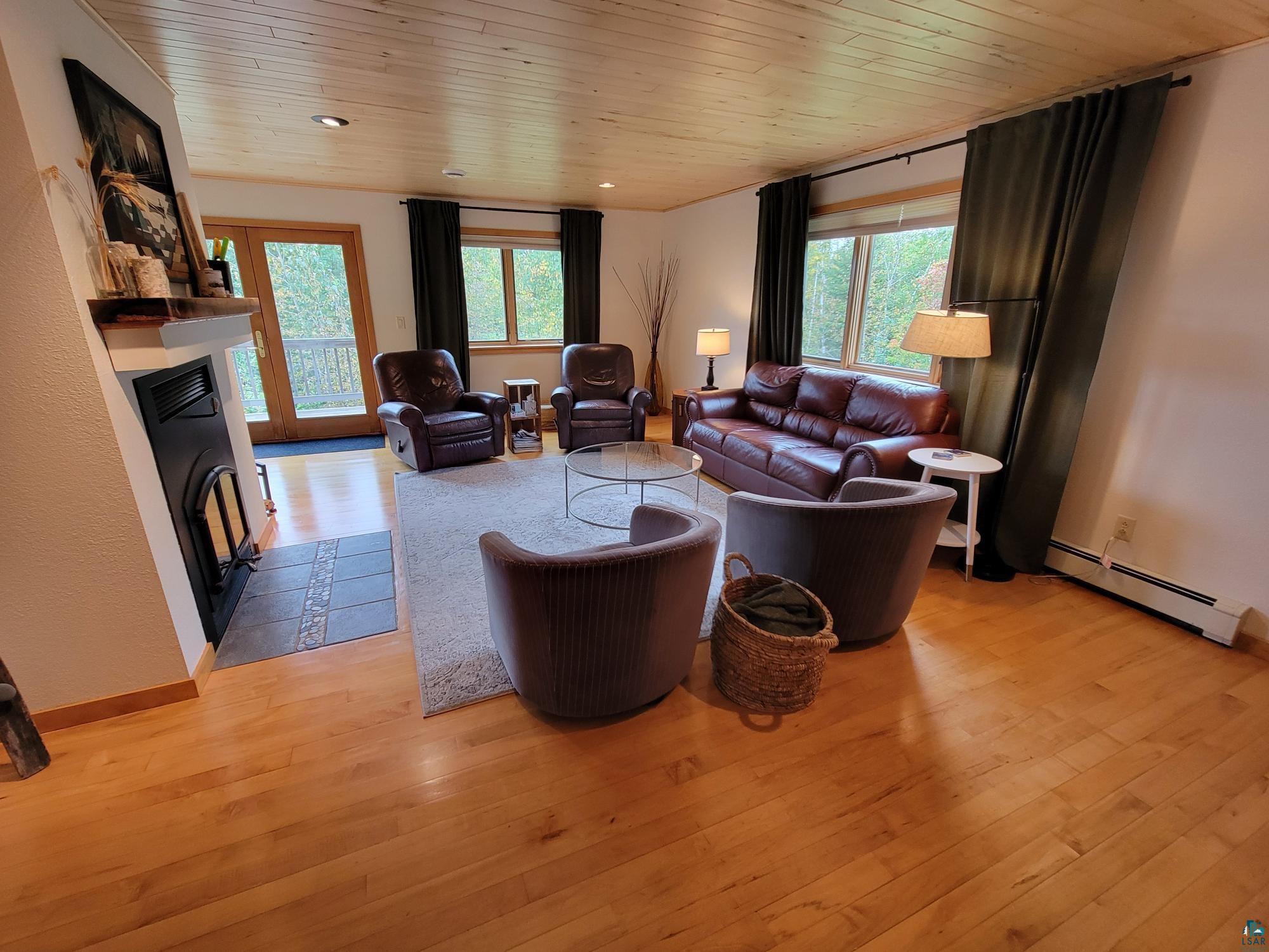 184 Fall River Road Grand Marais, MN 55604 - Photo 15 of 50 Living room with light wood-type flooring, a baseboard radiator, and a healthy amount of sunlight
