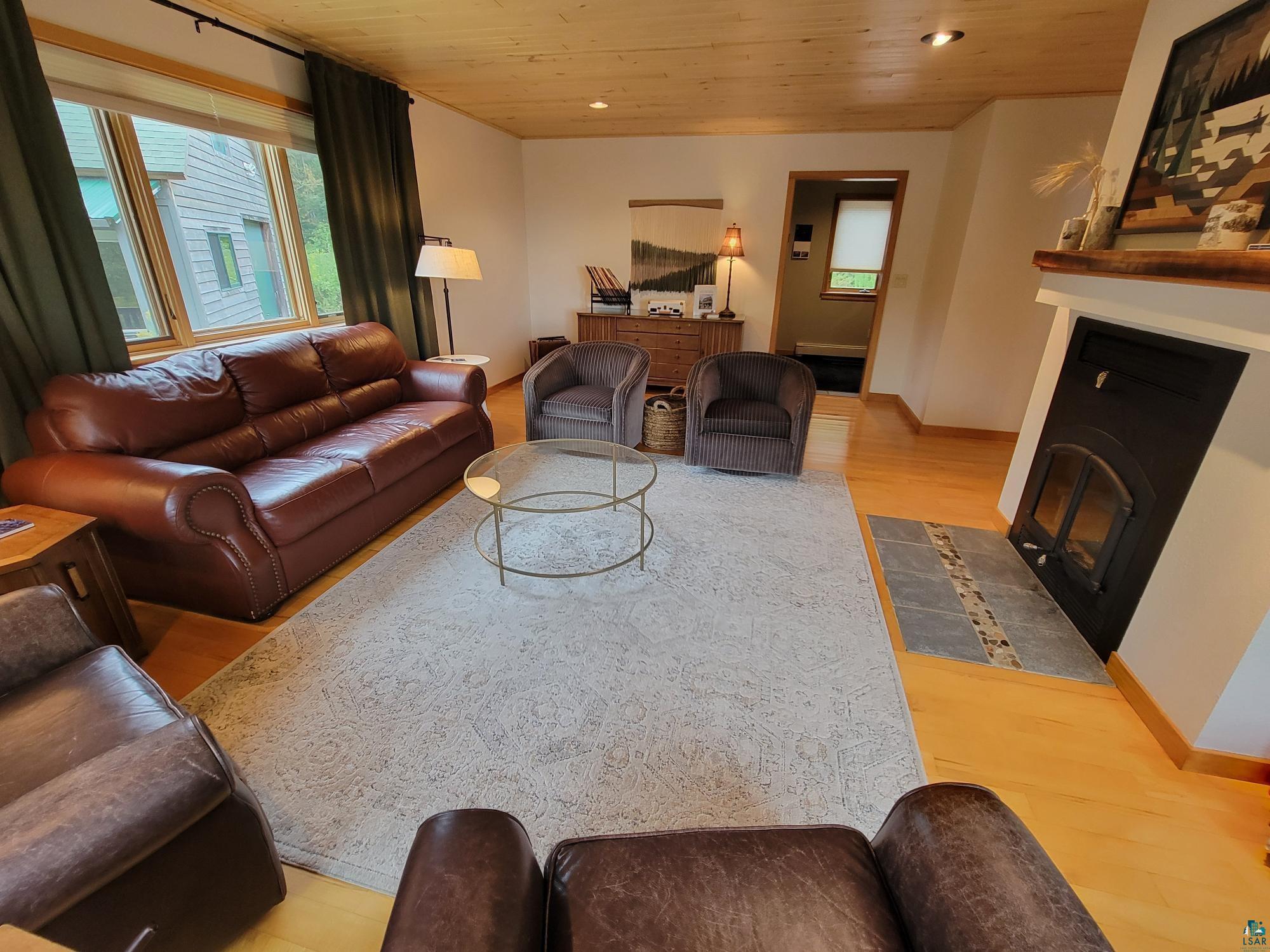 184 Fall River Road Grand Marais, MN 55604 - Photo 20 of 50 Living room with wood ceiling, a fireplace, and light hardwood / wood-style floors