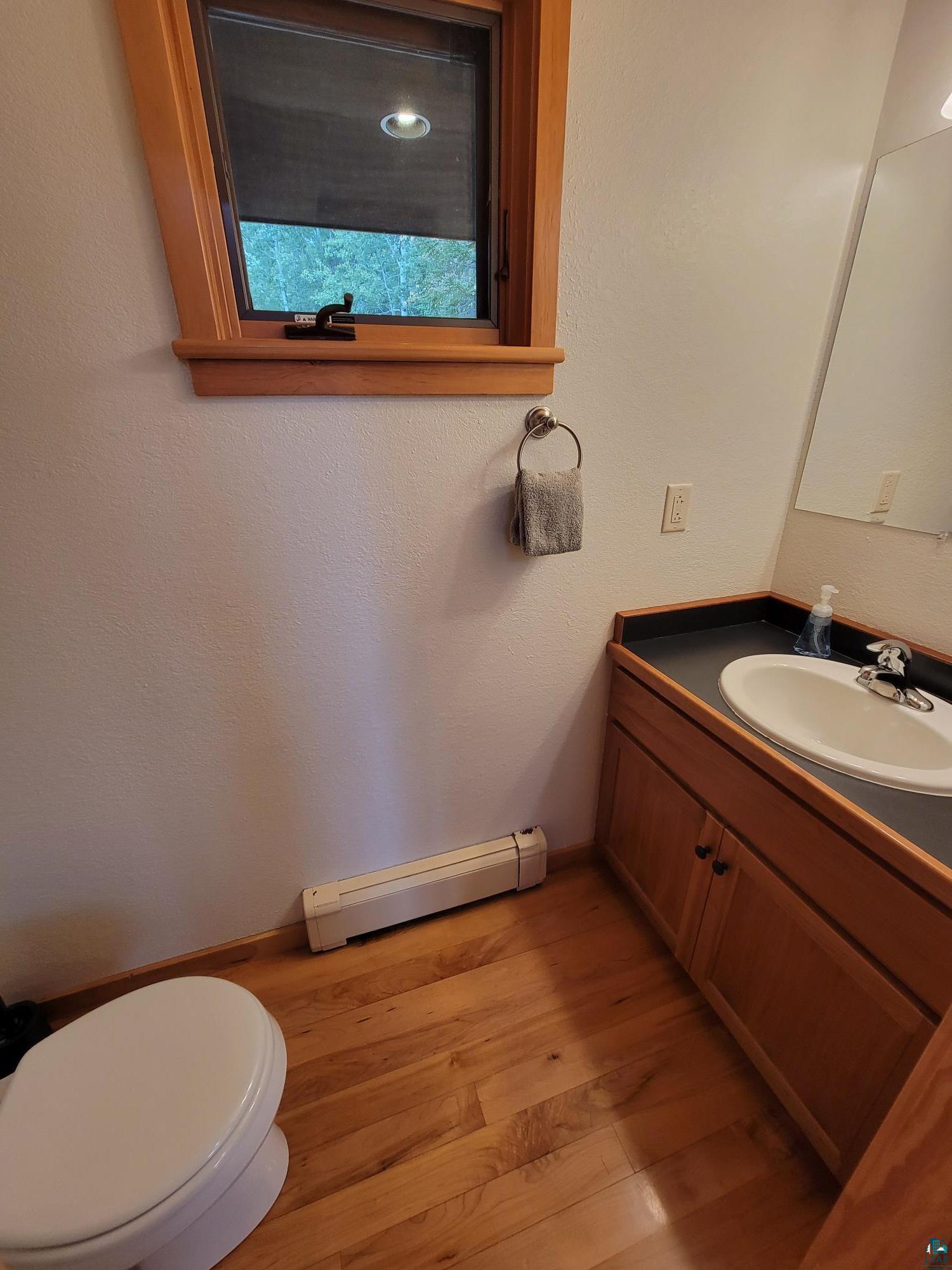 184 Fall River Road Grand Marais, MN 55604 - Photo 22 of 50 Bathroom with a baseboard heating unit, vanity, toilet, and hardwood / wood-style floors