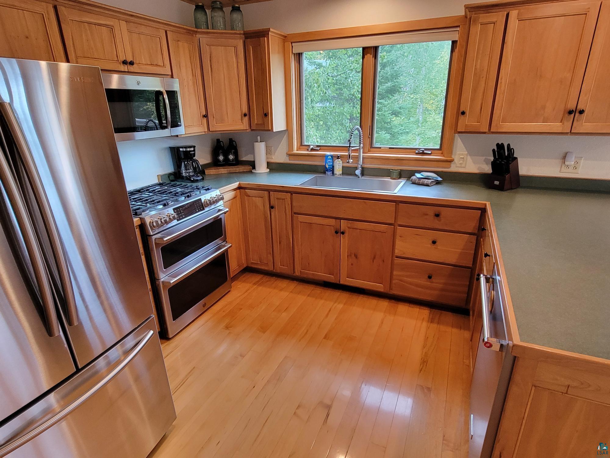 184 Fall River Road Grand Marais, MN 55604 - Photo 23 of 50 Kitchen with appliances with stainless steel finishes, light hardwood / wood-style flooring, and sink