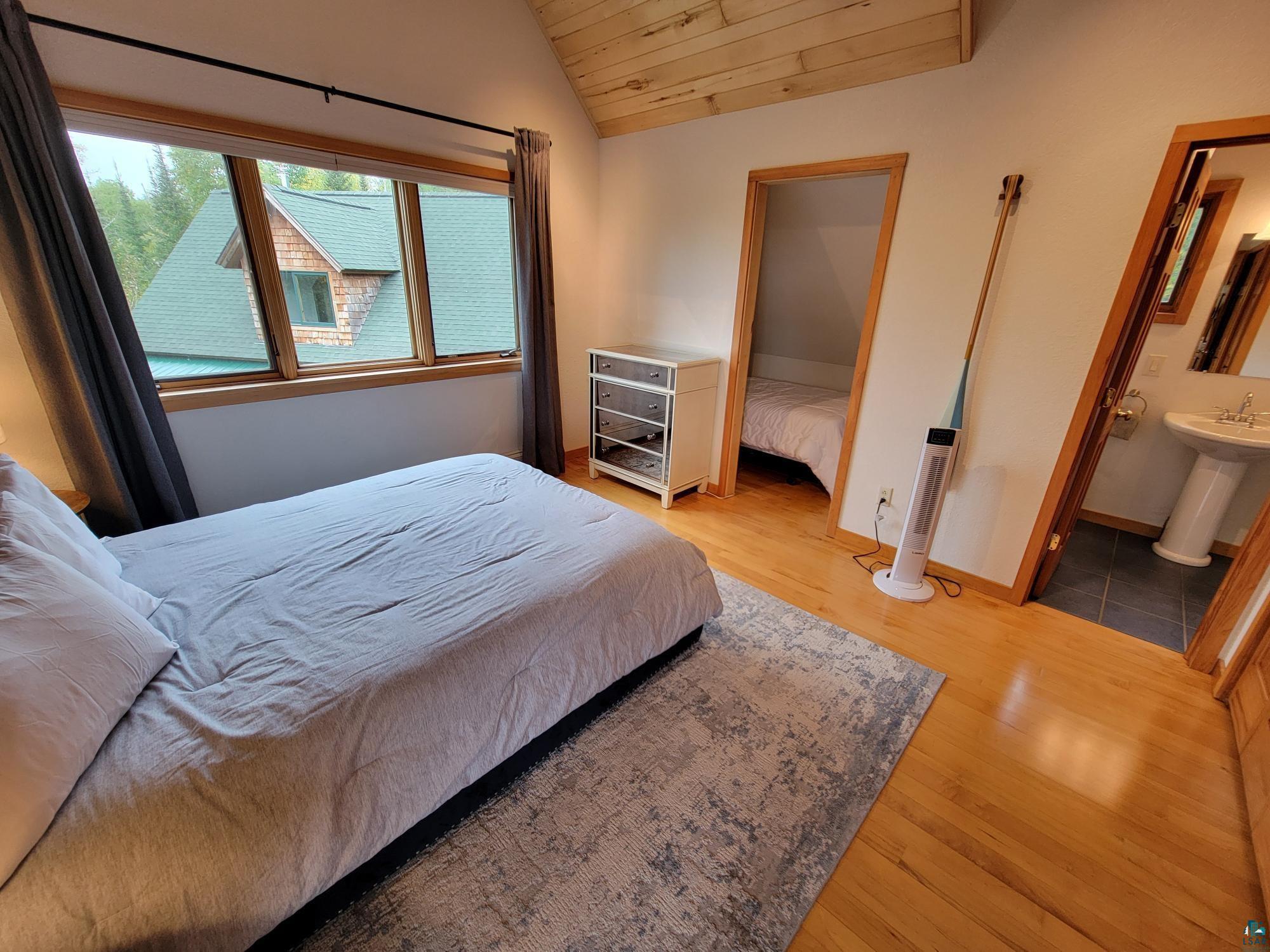 184 Fall River Road Grand Marais, MN 55604 - Photo 30 of 50 Bedroom with lofted ceiling, wood-type flooring, ensuite bathroom, and wood ceiling