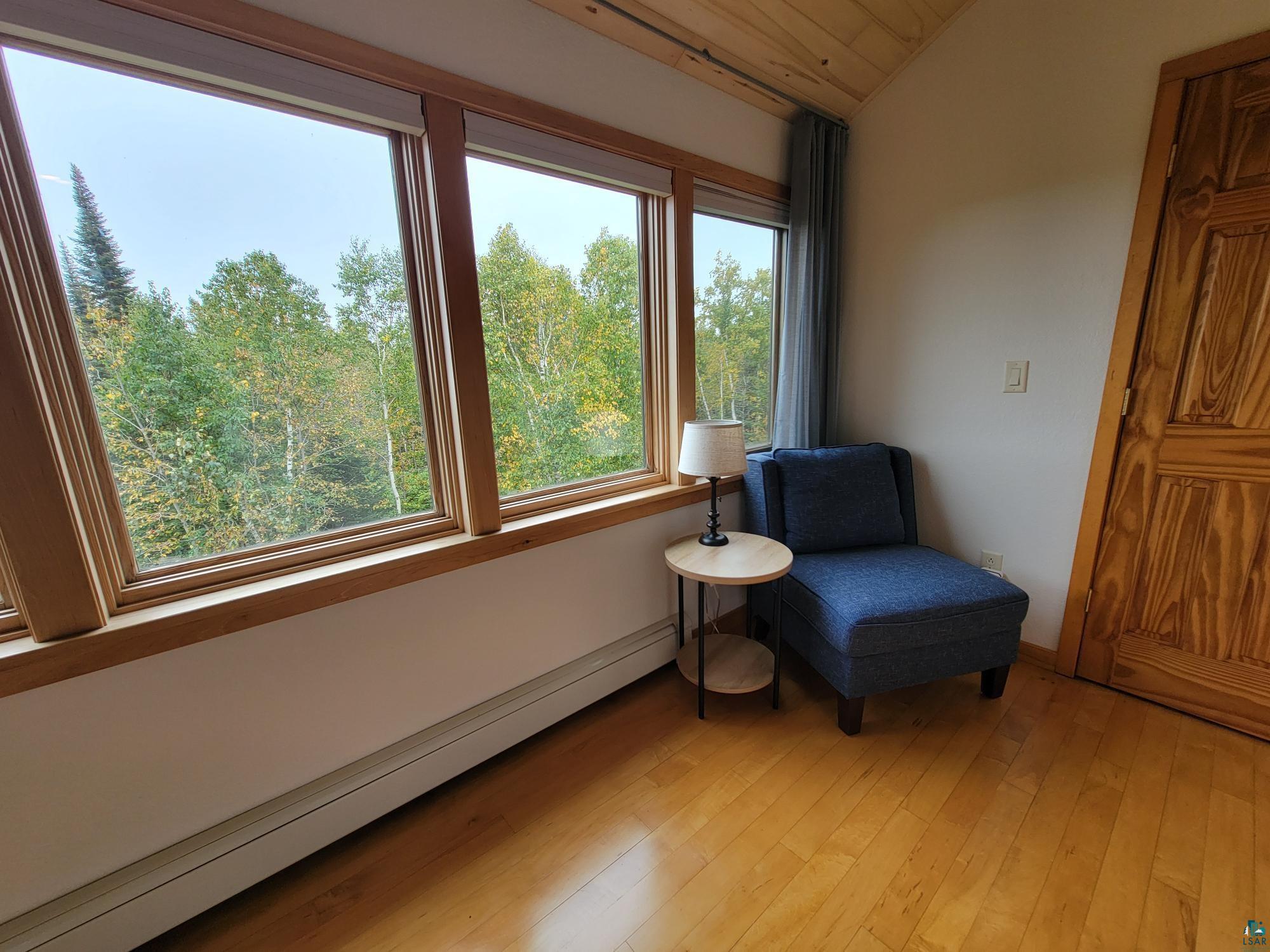 184 Fall River Road Grand Marais, MN 55604 - Photo 36 of 50 Living area featuring baseboard heating, light hardwood / wood-style floors, and vaulted ceiling