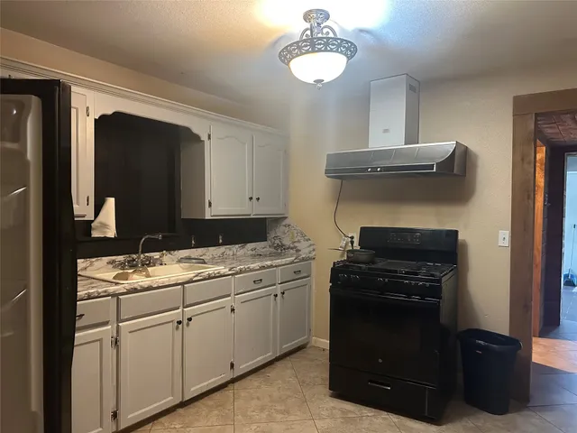 a kitchen with a sink dishwasher stove and white cabinets