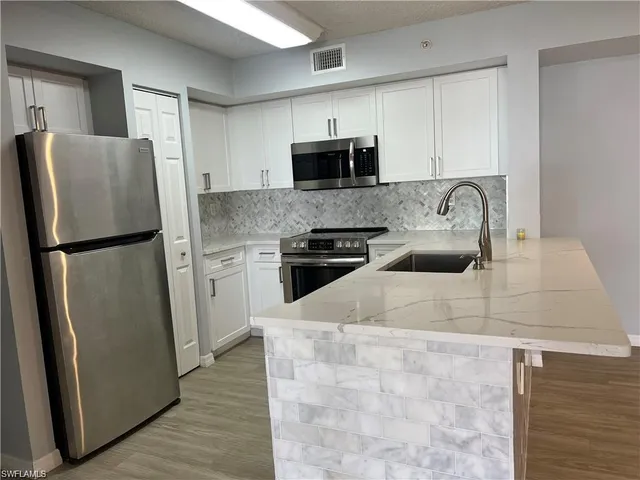 a kitchen with stainless steel appliances granite countertop a refrigerator a stove top oven a sink and dishwasher